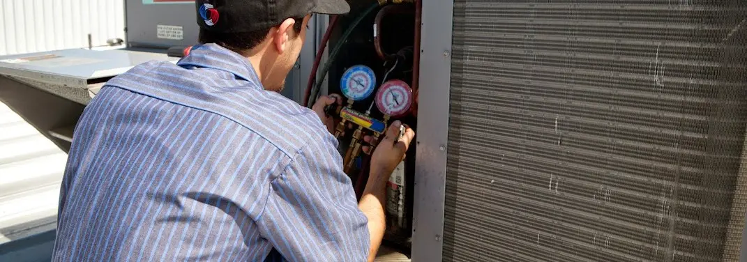 HVAC technician servicing a condenser unit in Steilacoom
